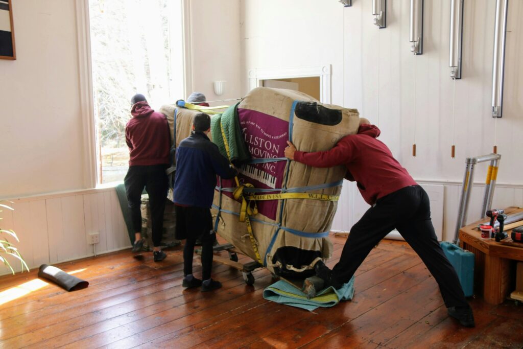 A group of people collaboratively lifting and moving a large piece of furniture across a room.