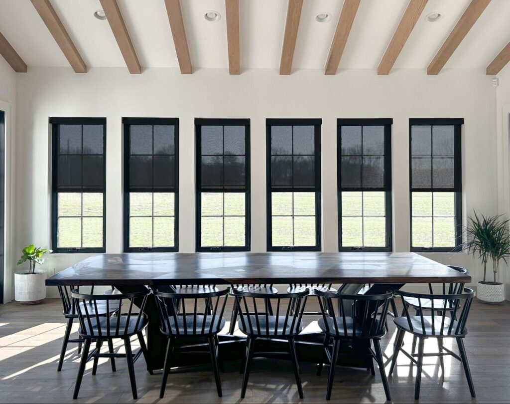 A dining room featuring black blinds and exposed wooden beams, creating a modern yet rustic atmosphere.