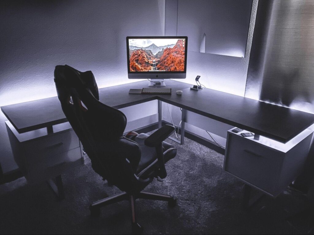 A computer desk featuring a monitor and an ergonomic chair, arranged for a productive workspace.