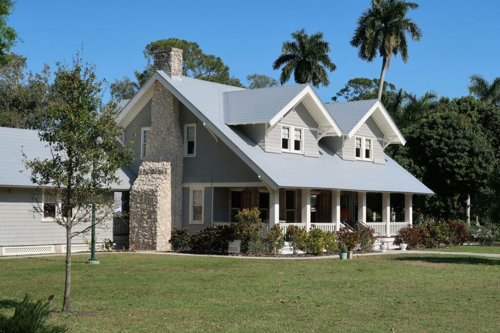 A blue and white house with a well-maintained lawn under a bright blue sky.